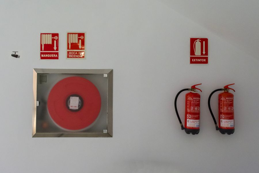 Extintores, boca de incendio y señalización de emergencia en una pared